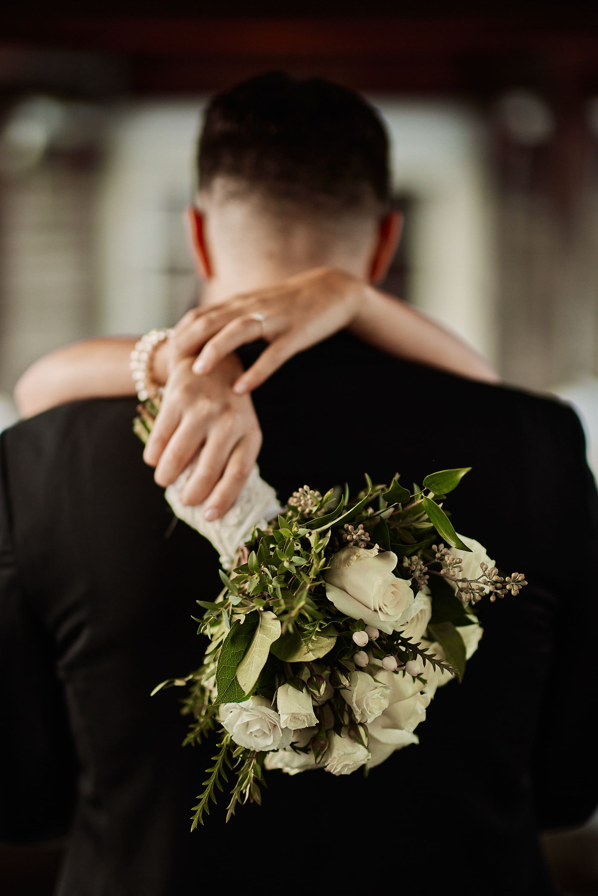 Moody portrait of a bride and groom embracing from behind